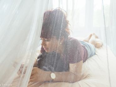 kisgyerek fekszik a szúnyogháló alatt az ágyban