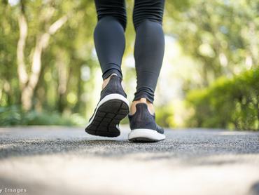 Nő a parkban, betonozott felületen gyalogol, de csak a lába látszik sportcipőben