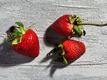 három szem eper egy durva felületű asztalon