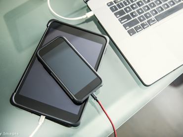 egy telefon, egy laptop és egy ipad az asztalon