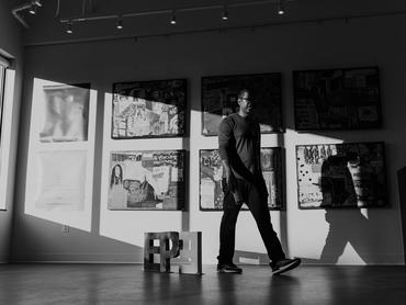 A male dentist of Indian descent walks past artwork he created and has on display in the waiting room of the dental clinic he owns.