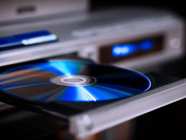 DVD lemezt tesz be a lejátszóba egy férfi kéz