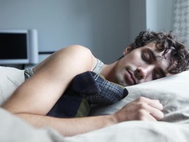 Férfi közeli fotója ahogy az ágyban alszik