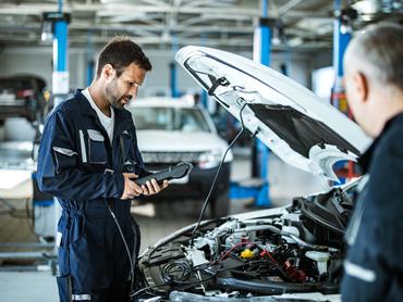 Egy fiatal szerelő egy műhelyben diagnosztikai eszközzel elemzi az autó teljesítményét.