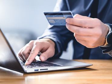 Biztonságos online fizetés és elektronikus átutalás. Fizessen digitális technológiával! Férfi, aki hitelkártyával és laptopjával jelentkezik be az internetes bankba. Pénzügyi biztonság a csalások, fenyegetések és visszaélések megelőzése érdekében.