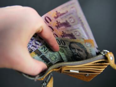 A képen egy kézben tartott pénztárca látható, benne néhány magyar forintos bankjegy. Három tízezer forintos bankjegy és egy húszezer forintos bankjegy. Összesen 50 000 HUF. A háttér fekete. A kép színtelítettségét javították.