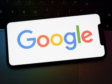 A Google logója megjelenik egy laptop billentyűzetére helyezett okostelefon képernyőjén. A Google és az Apple 2026. január 14-én, a franciaországi Créteilben együttműködési megállapodást kötött a Gemini Siri-be és az egész ökoszisztémába történő integrálásáról. (Fotó: Samuel Boivin/NurPhoto, Getty Images)