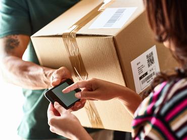 A futár átadja a csomagot, és megkéri a női ügyfelet, hogy adja meg az elektronikus aláírását; kézbesítés, átvétel, hatékonyság