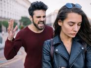 Férfi az utcán a nő mögött halad és kiabál vele. A nő lehajtja a fejét és szomorú.