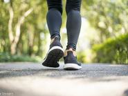 Nő a parkban, betonozott felületen gyalogol, de csak a lába látszik sportcipőben