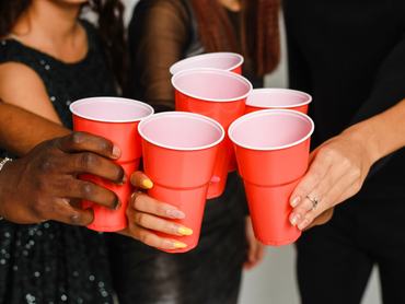 Hat barát derékig felhúzva szórakozik és alkoholt iszik egy újévi bulin, elszigetelt fehér háttérrel. Egy csoport vidám, különböző nemzetiségű barát koccint piros poharakkal egy bulin a stúdióban.