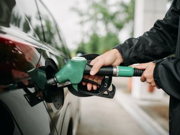 Egy autós benzint tankol az autójába a benzinkúton