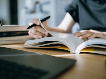 Egy diáklány lapozgatja a tankönyvet a dolgozat vagy érettségi vizsga közben.