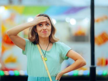 Egy fiatal nő az utcán állva a homlokára teszi a kezét, mert rájött, hogy valamit elfelejtett