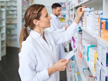 Gyógyszerészek keresnek gyógyszereket a patikai polcon