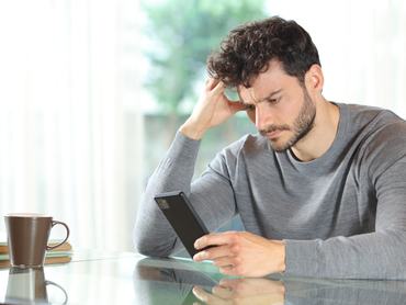 Aggódó férfi nézi az okostelefonját