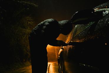 Man with hood trying to break into car.
